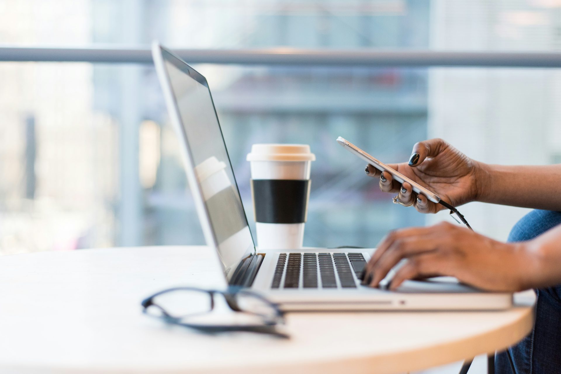 person using smartphone and MacBook